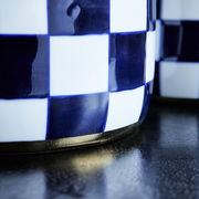 Nahaufnahme einer handbemalten Vase Harlekin mit blau-weißem Karomuster und goldener Basis.