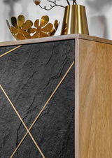 Detailansicht einer Kommode mit schwarzer Steinoptik und goldenen Akzenten, kombiniert mit einer Holzseite. Obenauf stehen goldene Dekorationsgegenstände.