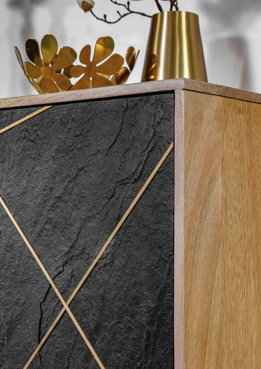 Detailansicht einer Kommode mit schwarzer Steinoptik und goldenen Akzenten, kombiniert mit einer Holzseite. Obenauf stehen goldene Dekorationsgegenstände.