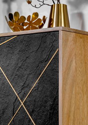 Detailansicht einer Kommode mit schwarzer Steinoptik und goldenen Akzenten, kombiniert mit einer Holzseite. Obenauf stehen goldene Dekorationsgegenstände.