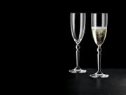 Zwei elegante Champagnerflöten aus klarem Glas auf schwarzem Hintergrund, eine leer und eine mit Sekt gefüllt, frontale Produktansicht