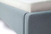 Nahaufnahme eines blauen Polsterbetts mit sichtbarer Matratze, seitliche Perspektive.