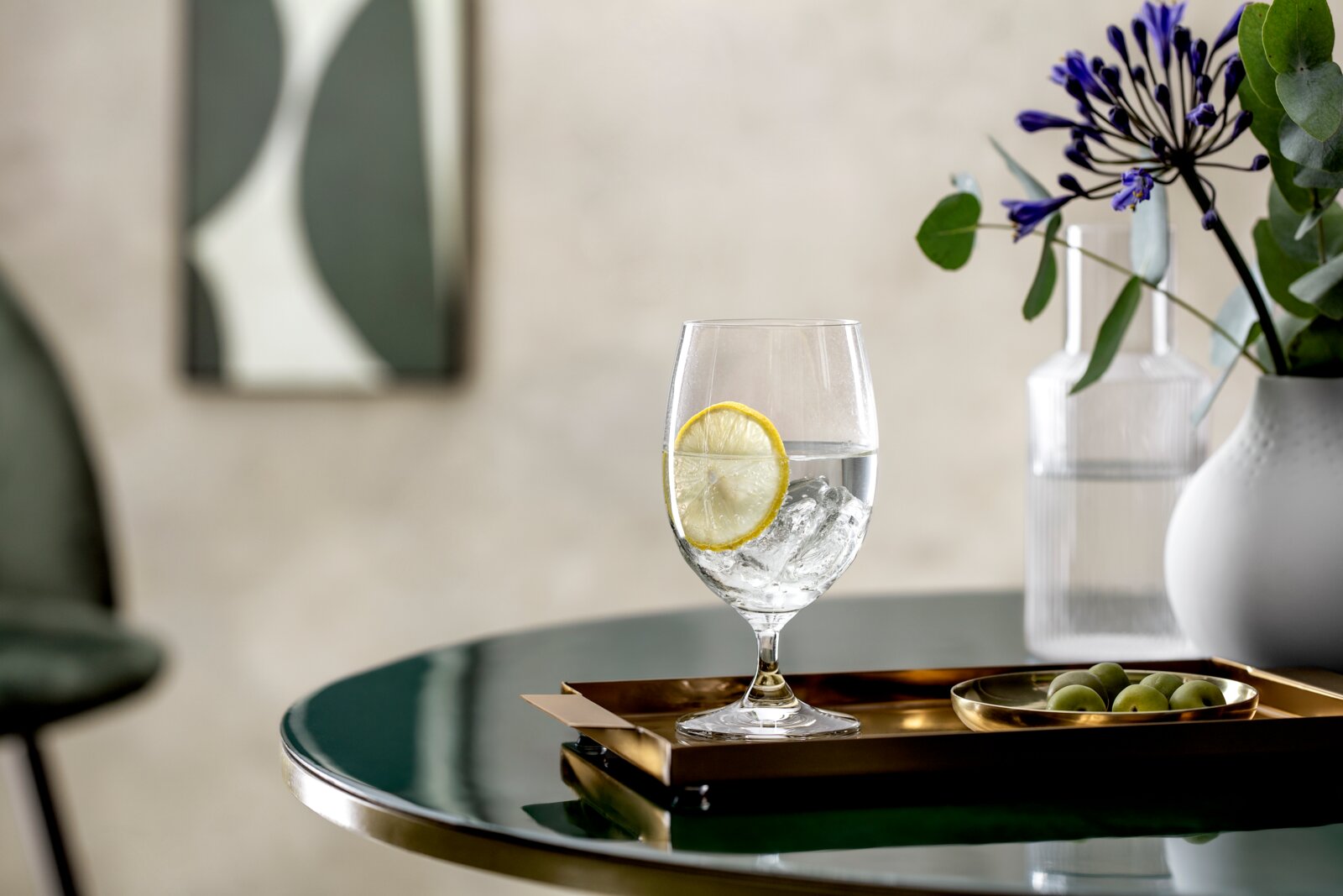 Villeroy & Boch Set van 4 waterbekers LA DAVINA Een elegante waterkelk met ijsblokjes en een schijfje citroen, op een gouden dienblad op een tafel, omringd door een stijlvolle decoratie. Perspectief: zijaanzicht.