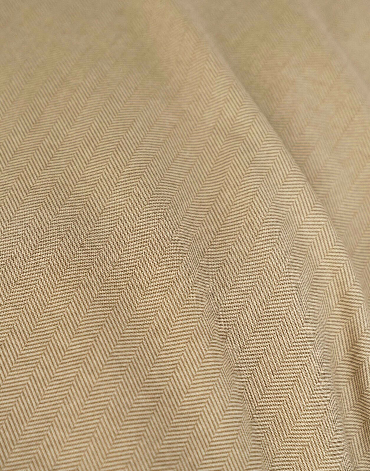 Nahaufnahme einer Bettwäsche mit Fischgrätenmuster in Beige, diagonale Perspektive