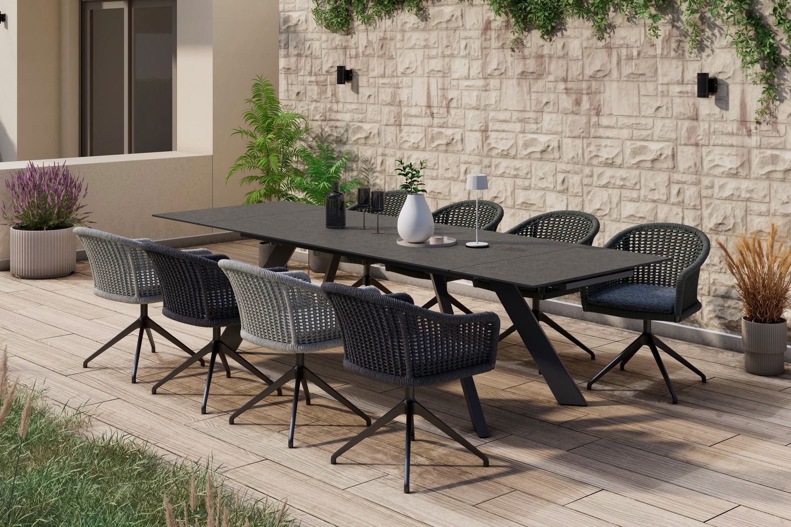 Amatio Fauteuil CIRCLE Moderner Armlehnstuhl auf einer Terrasse, seitliche Perspektive, umgeben von Pflanzen und einem großen Tisch.