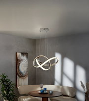 Moderne LED-Pendelleuchte mit verschlungenen, ringförmigen Lichtbändern in Chromoptik über einem runden Esstisch in grauem Wohnraum, Ansicht leicht von unten (Untersicht)