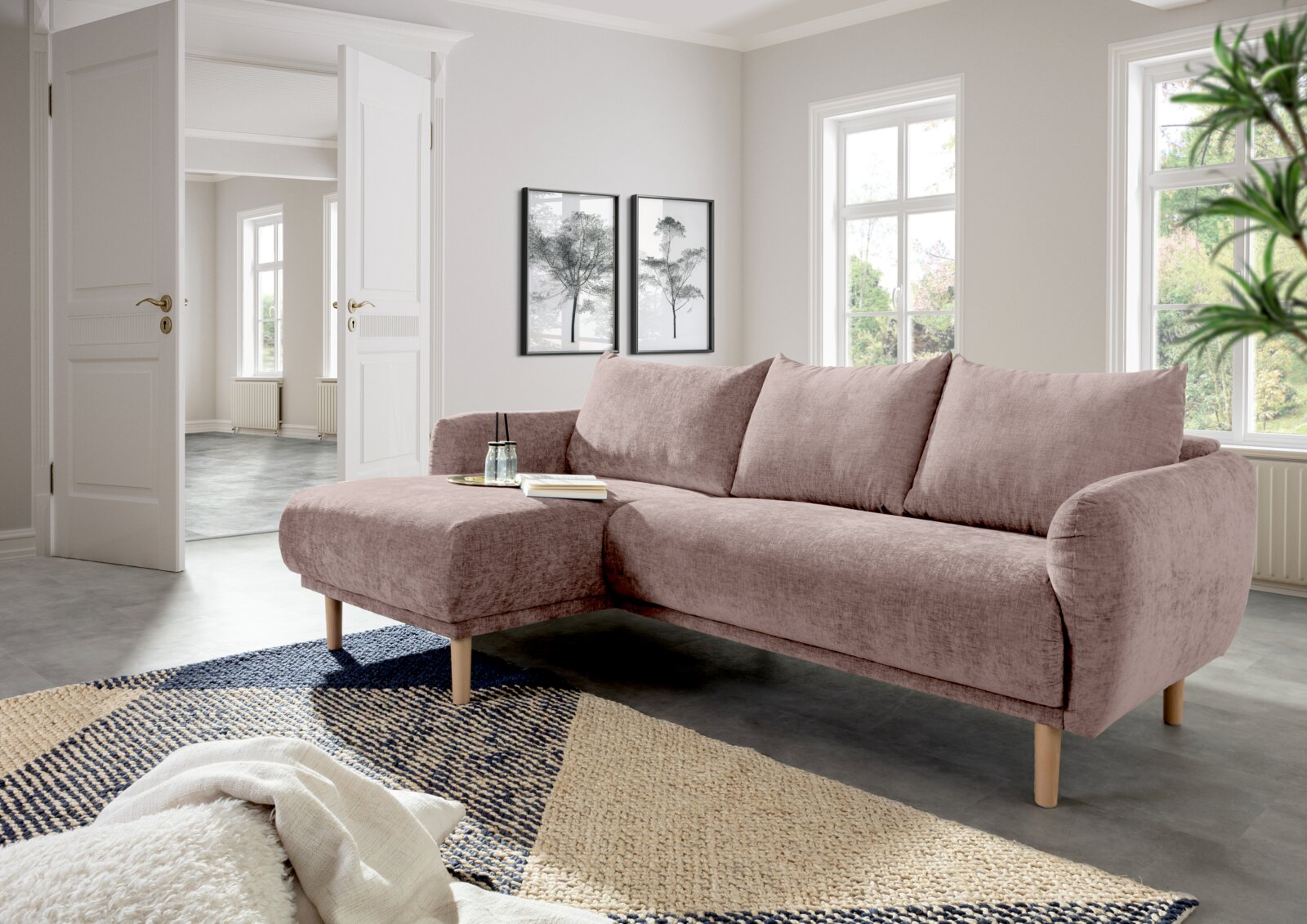 Rosa Ecksofa mit Holzbeinen in einem modernen Wohnzimmer, Perspektive von vorne links.