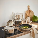 Küchenansicht mit einem sechsteiligen Topfset Twin Classic aus Edelstahl, bestehend aus Töpfen und Pfannen, auf einem Herd und einer Arbeitsplatte arrangiert.