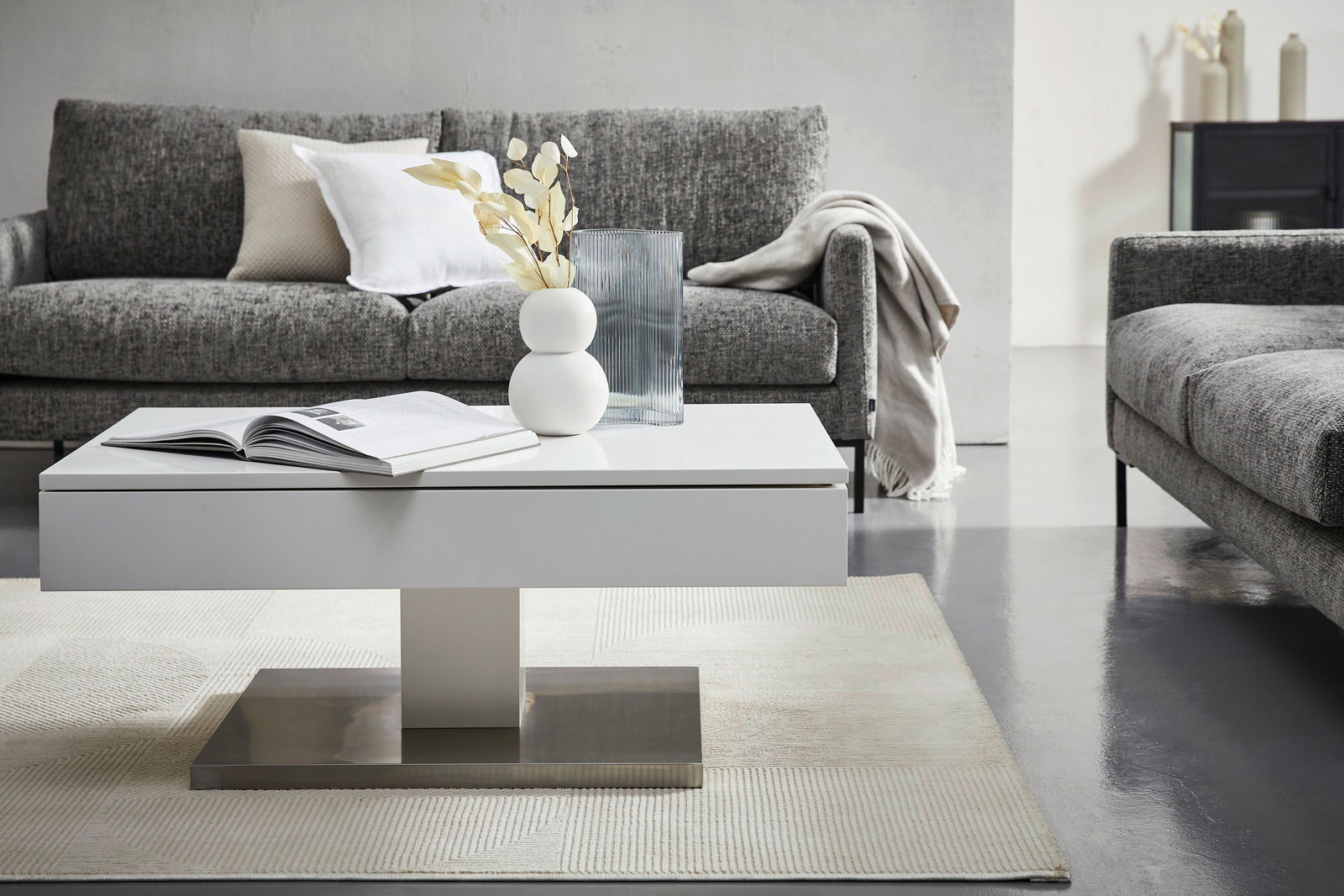 Z2 Couchtisch SHIRA Moderner weißer Couchtisch in einem stilvollen Wohnzimmer, frontal fotografiert, mit grauem Sofa im Hintergrund und dekorativen Elementen auf dem Tisch.