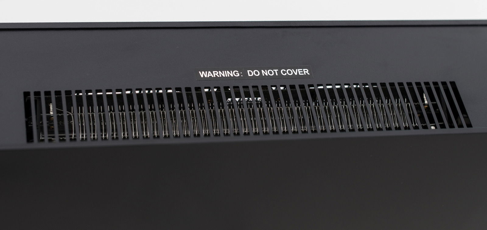 Nahaufnahme der Lüftungsschlitze eines Elektrokamins mit Warnhinweis 'DO NOT COVER'.