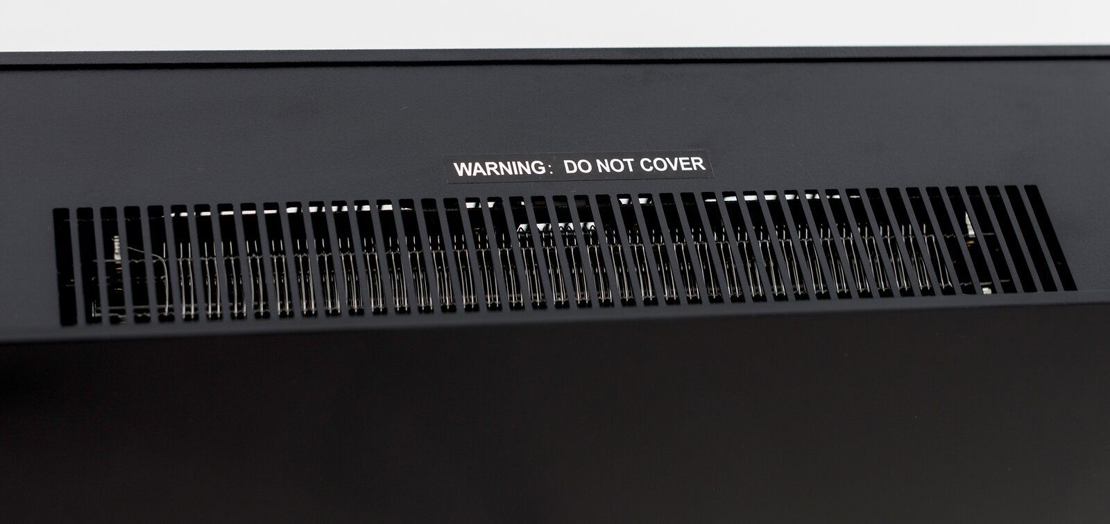 Nahaufnahme der Lüftungsschlitze eines Elektrokamins mit Warnhinweis 'DO NOT COVER'.