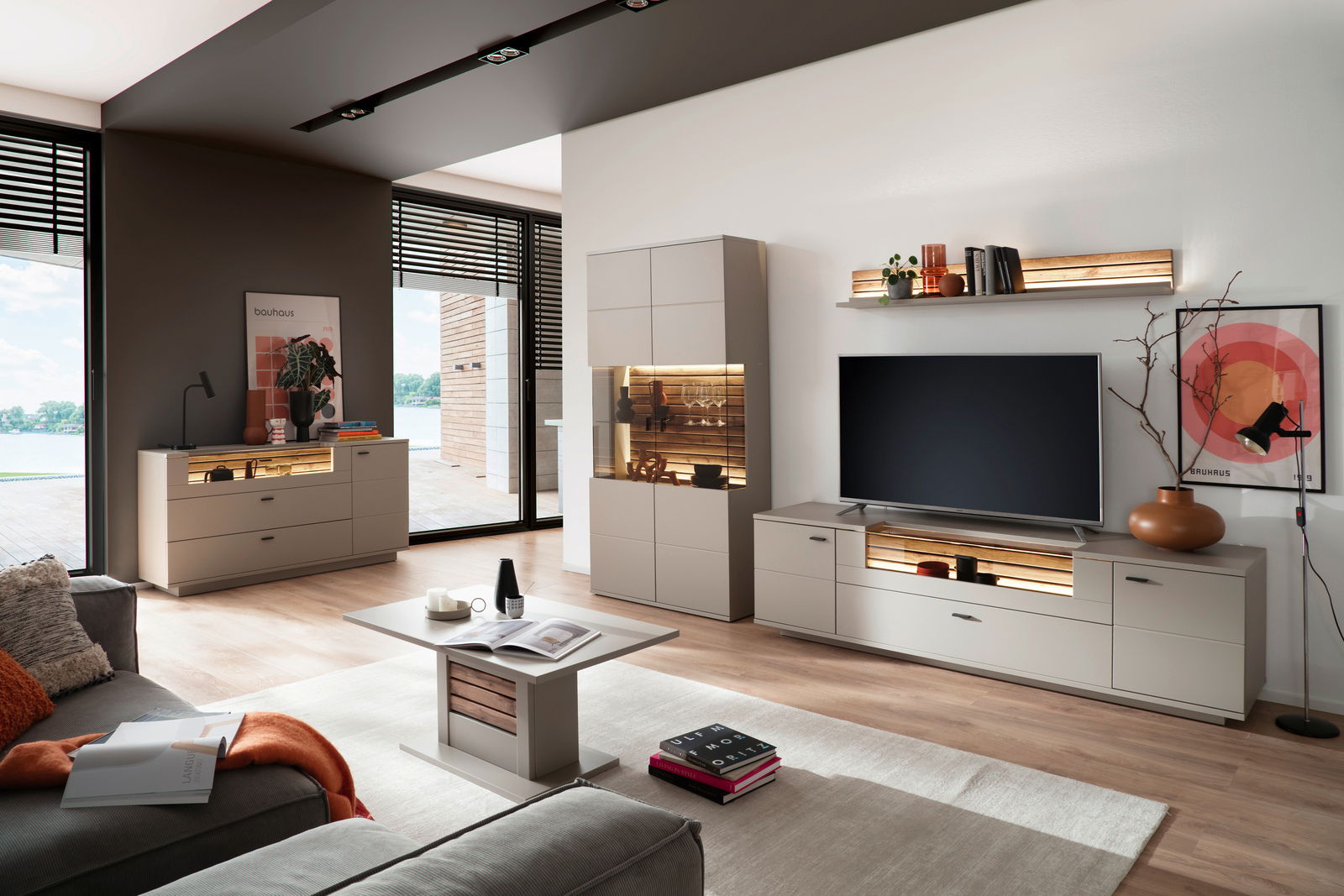 Zurbrüggen Wandboard LÜTTICH Moderne Wohnzimmermöbel mit Sideboard, Highboard, Wandboard und Esstisch in einem hellen Raum mit großen Fenstern, seitliche Perspektive.