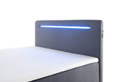 Boxbett mit grauem Kopfteil und integrierter blauer LED-Beleuchtung, seitliche Perspektive