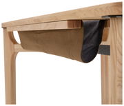 Nahaufnahme eines Schreibtisches aus Holz mit einer hängenden Stofftasche unter der Tischplatte, seitliche Perspektive