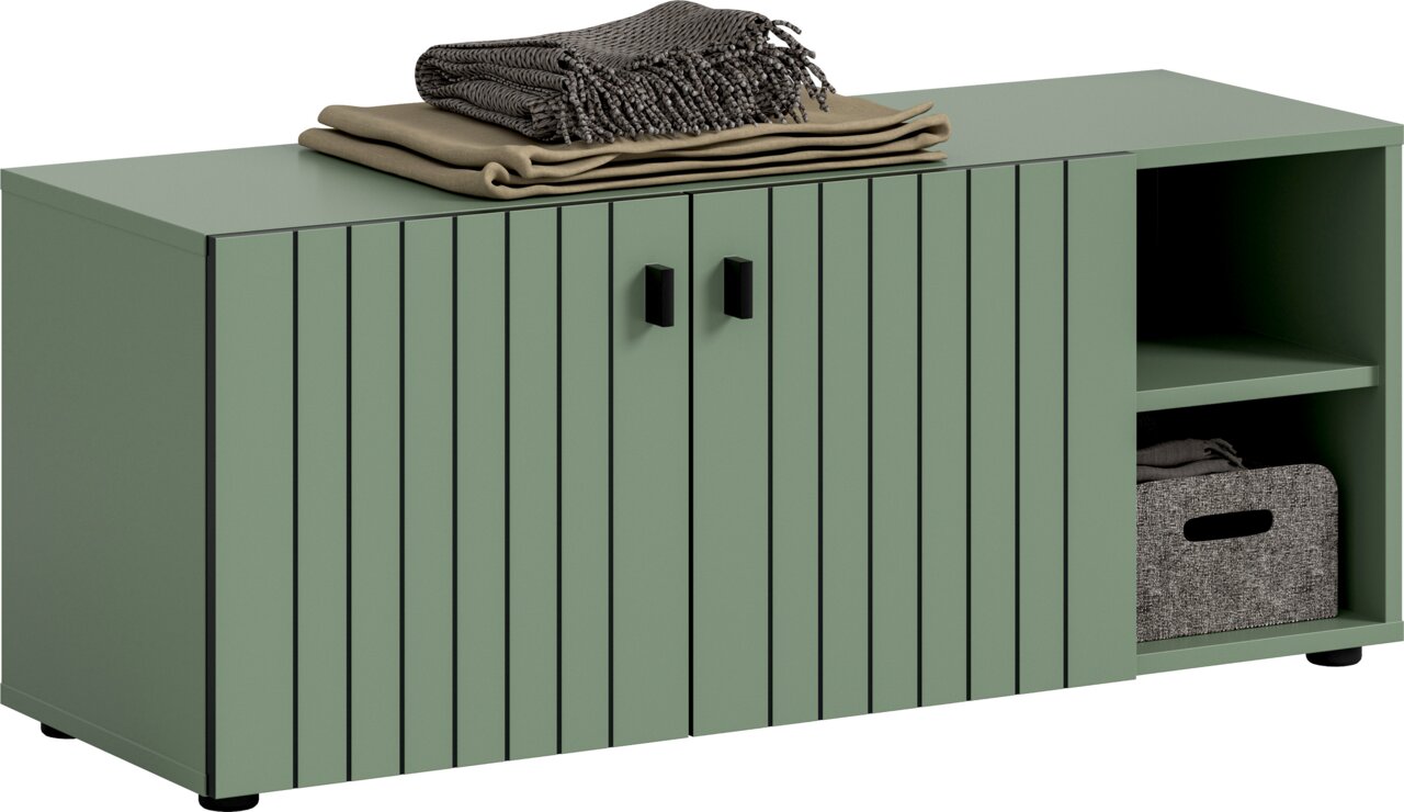 MID.YOU Sitzbank STATION Salbeigrünes Sideboard mit geriffelter Front, zwei Türen mit schwarzen Griffen und offenem Fach rechts; gefaltete Decken obenauf, Ansicht schräg von vorne links.