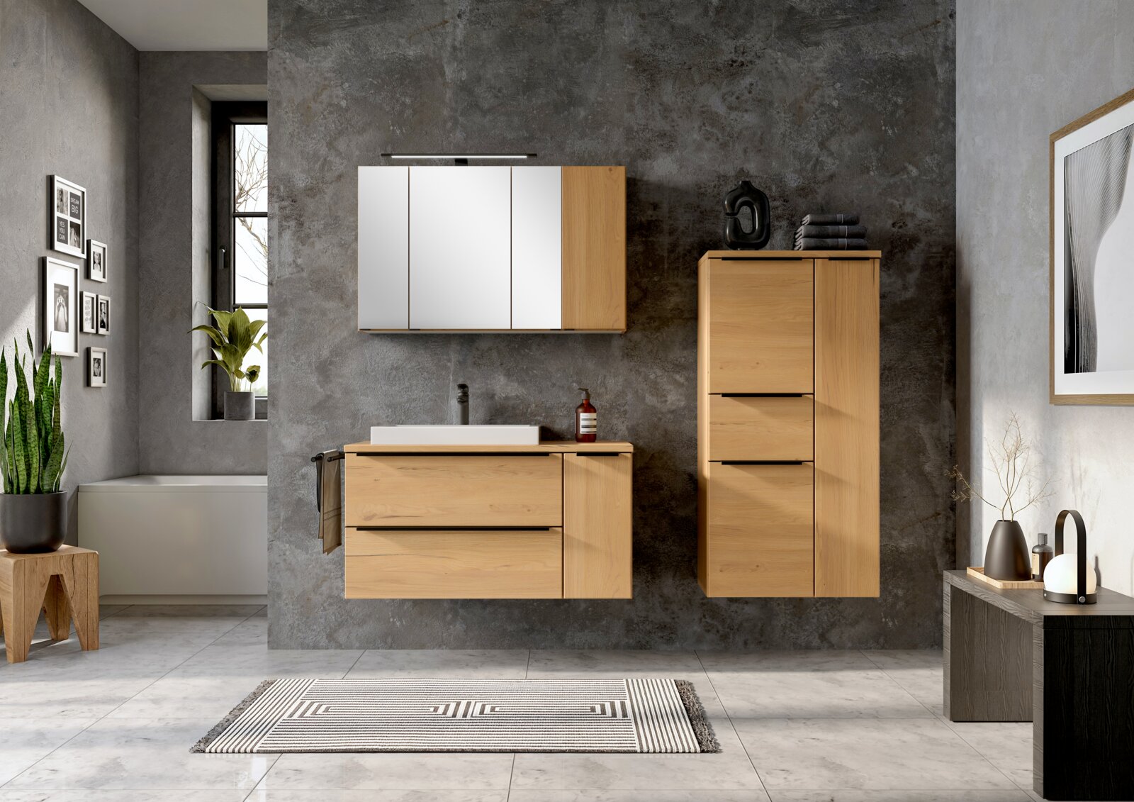 Frontale Ansicht eines modernen Badmöbel-Sets in hellem Holz mit Waschtischunterschrank, Spiegelschrank mit Beleuchtung und hohem Hochschrank vor grauer Betonoptik-Wand.
