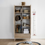 Offener Kleiderschrank mit zwei Türen und einer Schublade, gefüllt mit Kinderkleidung und Accessoires, aus frontaler Perspektive.