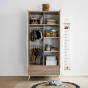 Offener Kleiderschrank mit zwei Türen und einer Schublade, gefüllt mit Kinderkleidung und Accessoires, aus frontaler Perspektive.