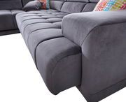 Graue Polsterrundecke in Nahaufnahme, Perspektive von der Seite mit bunten Kissen im Hintergrund.