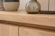 Nahaufnahme eines Sideboards aus hellem Holz mit dekorativen Vasen darauf, Perspektive von oben.