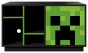 Schwarzes Sideboard mit offenen Fächern links und grüner Schiebetür mit pixeligem Creeper-Motiv rechts, Frontansicht.