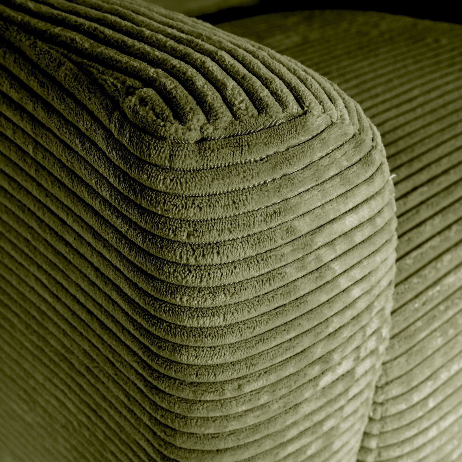 Stylife Fauteuil ATELLA Nahaufnahme der abgerundeten Ecke eines olivgrünen Cordstoff-Polsters mit breiten Rippen, schräg von oben fotografiert.