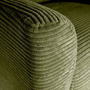Close-up van de afgeronde hoek van een olijfgroene corduroy bekleding met brede ribbels, schuin van bovenaf gefotografeerd.