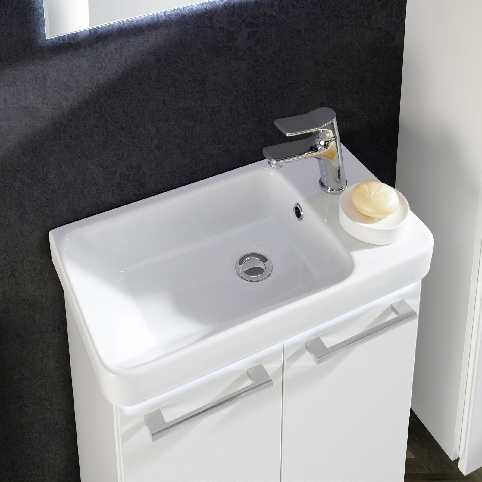 Moderner Waschtisch mit glänzendem Wasserhahn und Seifenschale, aus der Vogelperspektive fotografiert.