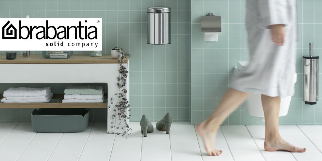 Een vrouw in een badjas loopt langs een badkamer met mintgroene tegels. Logo Brabantia