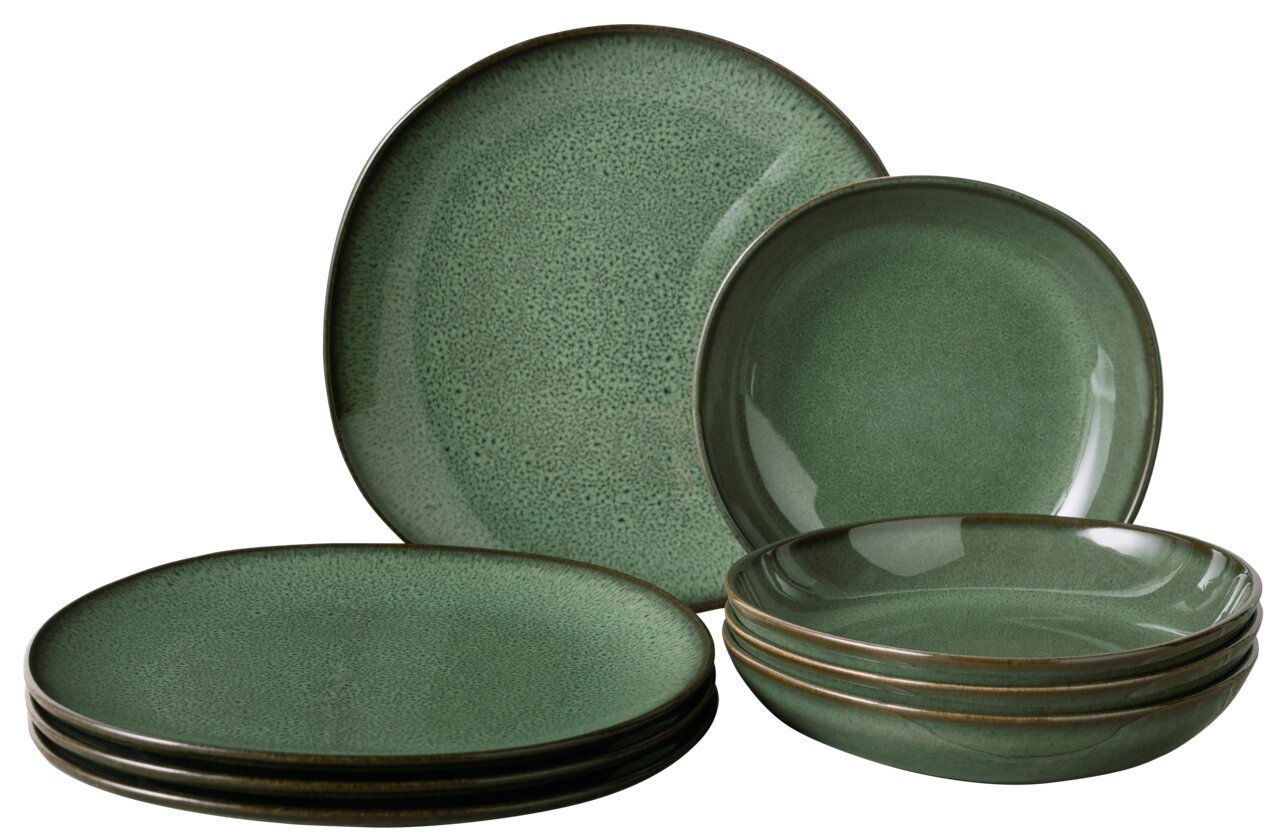 Grünes Keramikgeschirr-Set, bestehend aus flachen und tiefen Tellern, in einer leicht seitlichen Perspektive.