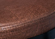 Nahaufnahme eines braunen Drehstuhlsitzes mit strukturierter Oberfläche, seitliche Perspektive