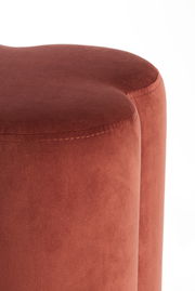 Nahaufnahme eines roten Sitzpuffs mit weicher, samtiger Oberfläche, seitliche Perspektive