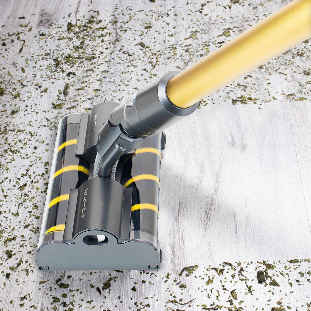 Staubsaugerbürste mit gelbem Griff auf hellem Holzboden, umgeben von Schmutz, aus der Vogelperspektive