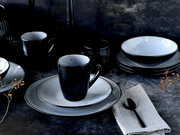 Elegantes Kombiservice 16-tlg in Schwarz und Grau, bestehend aus Tellern, Schalen und Tassen, auf einem dunklen Tisch arrangiert. Seitliche Perspektive.