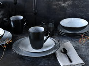 Elegantes Kombiservice 16-tlg in Schwarz und Grau, bestehend aus Tellern, Schalen und Tassen, auf einem dunklen Tisch arrangiert. Seitliche Perspektive.