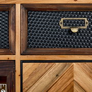 Nahaufnahme einer Kommode mit gemusterten Schubladenfronten aus Holz und Metall, perspektivisch von vorne aufgenommen.