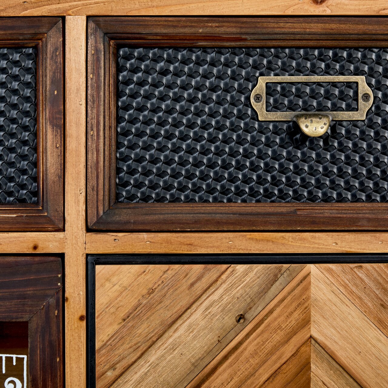Nahaufnahme einer Kommode mit gemusterten Schubladenfronten aus Holz und Metall, perspektivisch von vorne aufgenommen.