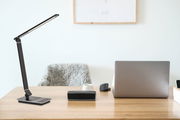 Moderne schwarze Schreibtischleuchte auf einem Holztisch, seitliche Perspektive.