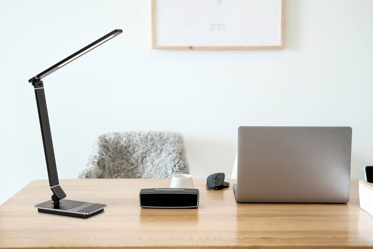 Novel Schreibtischleuchte Moderne schwarze Schreibtischleuchte auf einem Holztisch, seitliche Perspektive.