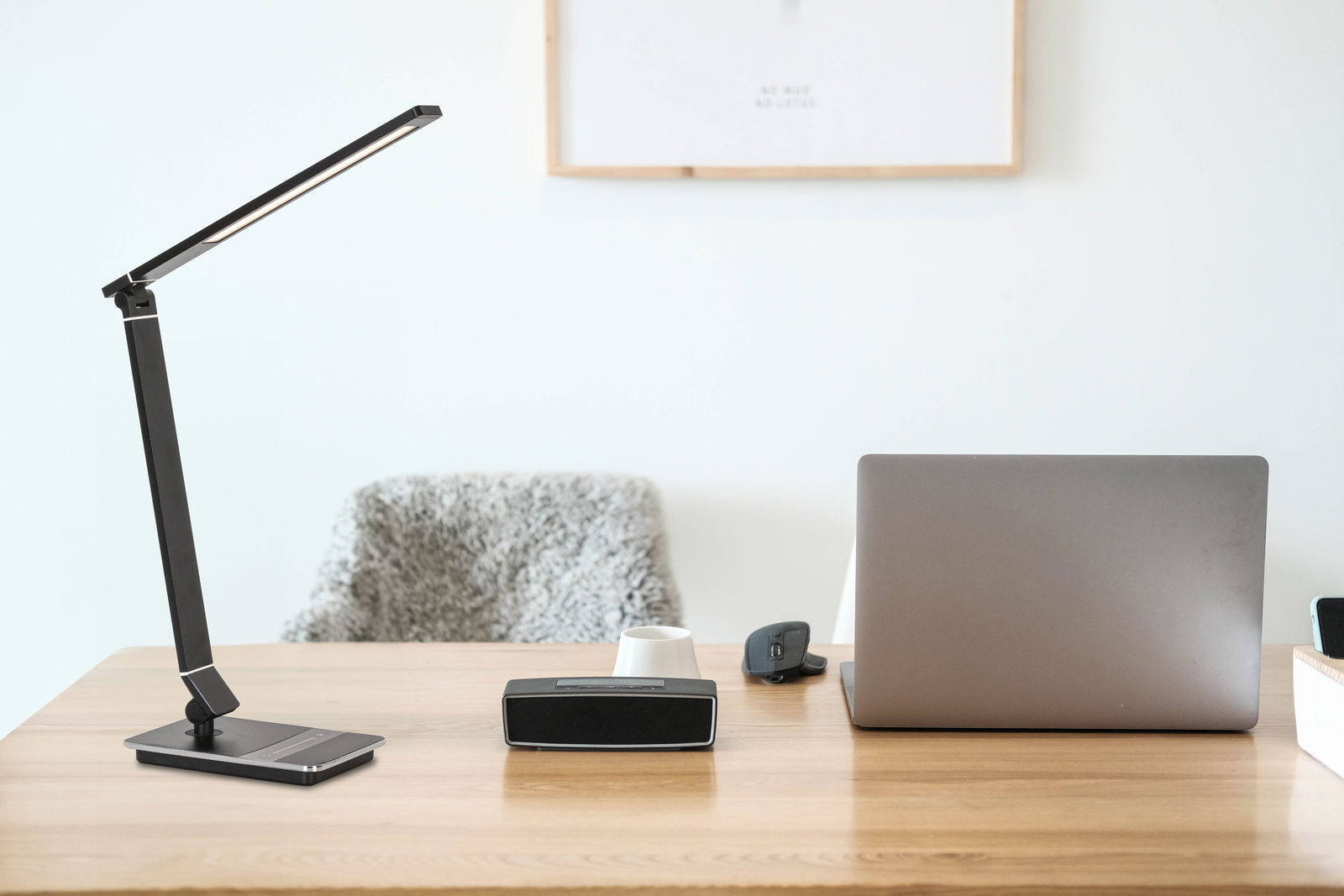 Moderne schwarze Schreibtischleuchte auf einem Holztisch, seitliche Perspektive.