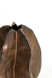 Nahaufnahme einer bronzefarbenen Vase mit organischer Form und glatter Oberfläche, von oben betrachtet.