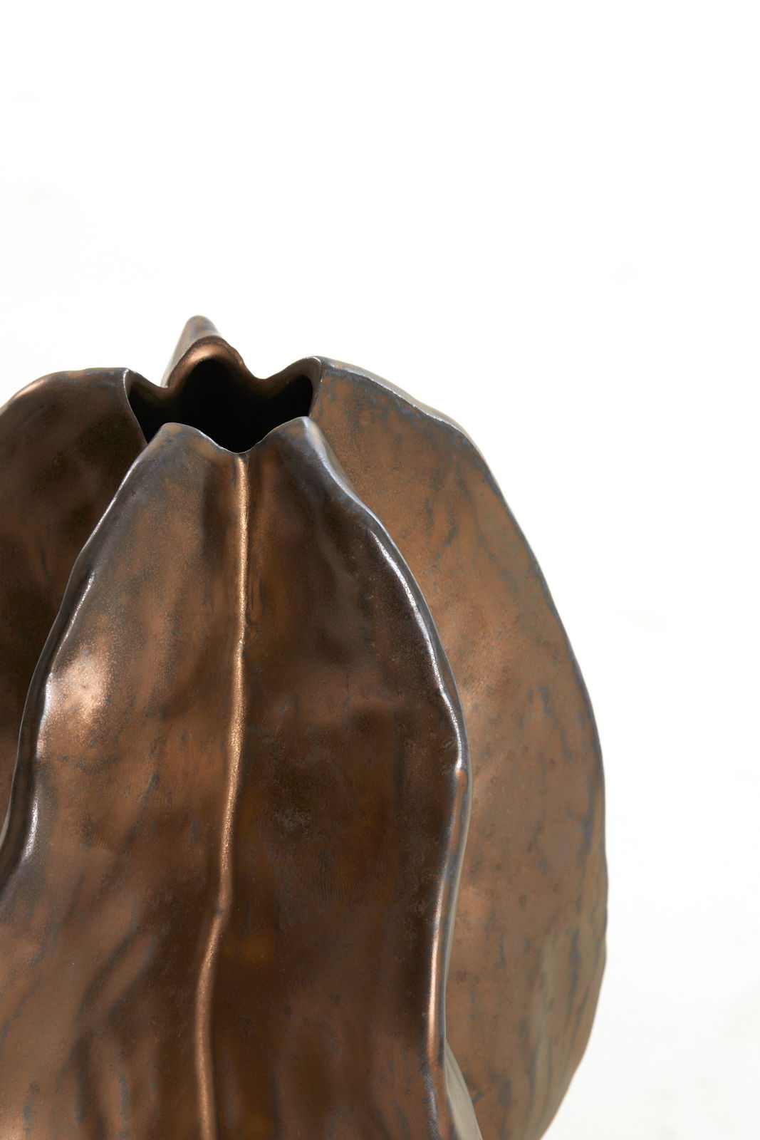 Nahaufnahme einer bronzefarbenen Vase mit organischer Form und glatter Oberfläche, von oben betrachtet.