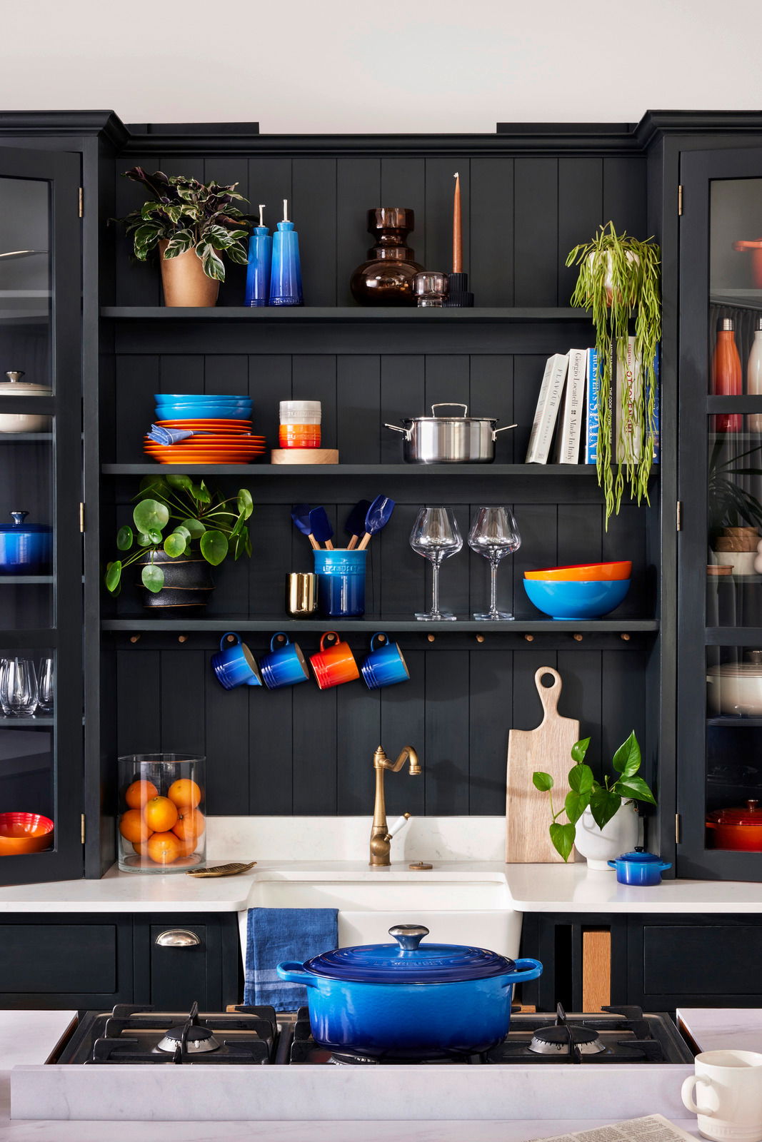 Blaue ovale Bräter auf einem Herd in einer stilvollen Küche, frontal betrachtet.