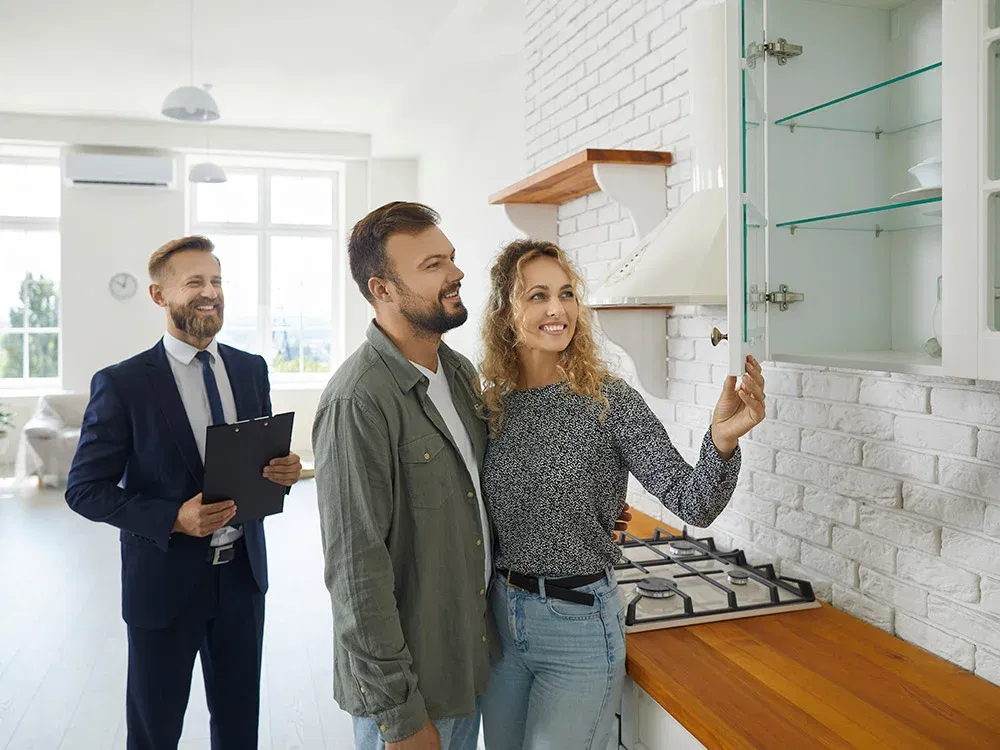 Ein glückliches Paar schaut sich mit einem Küchenberater eine helle Küche an