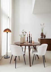 Runder Esstisch QUENZA aus Holz mit dekorativen Kerzen und Vasen, umgeben von vier gepolsterten Stühlen in einem hellen, modernen Raum. Seitliche Perspektive.