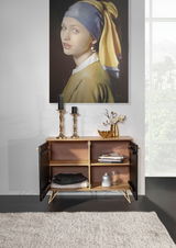 Kommode mit geöffneten Türen, dekoriert mit Kerzenhaltern und einer Vase, vor einem Gemälde, aus der Frontalperspektive fotografiert.