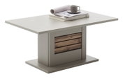 Quadratischer Esstisch in Grau mit zentralem Sockel und Holz-Lamellen-Akzent, auf der Tischplatte liegen Buch, Zeitschrift und Tasse; Ansicht schräg von vorne.