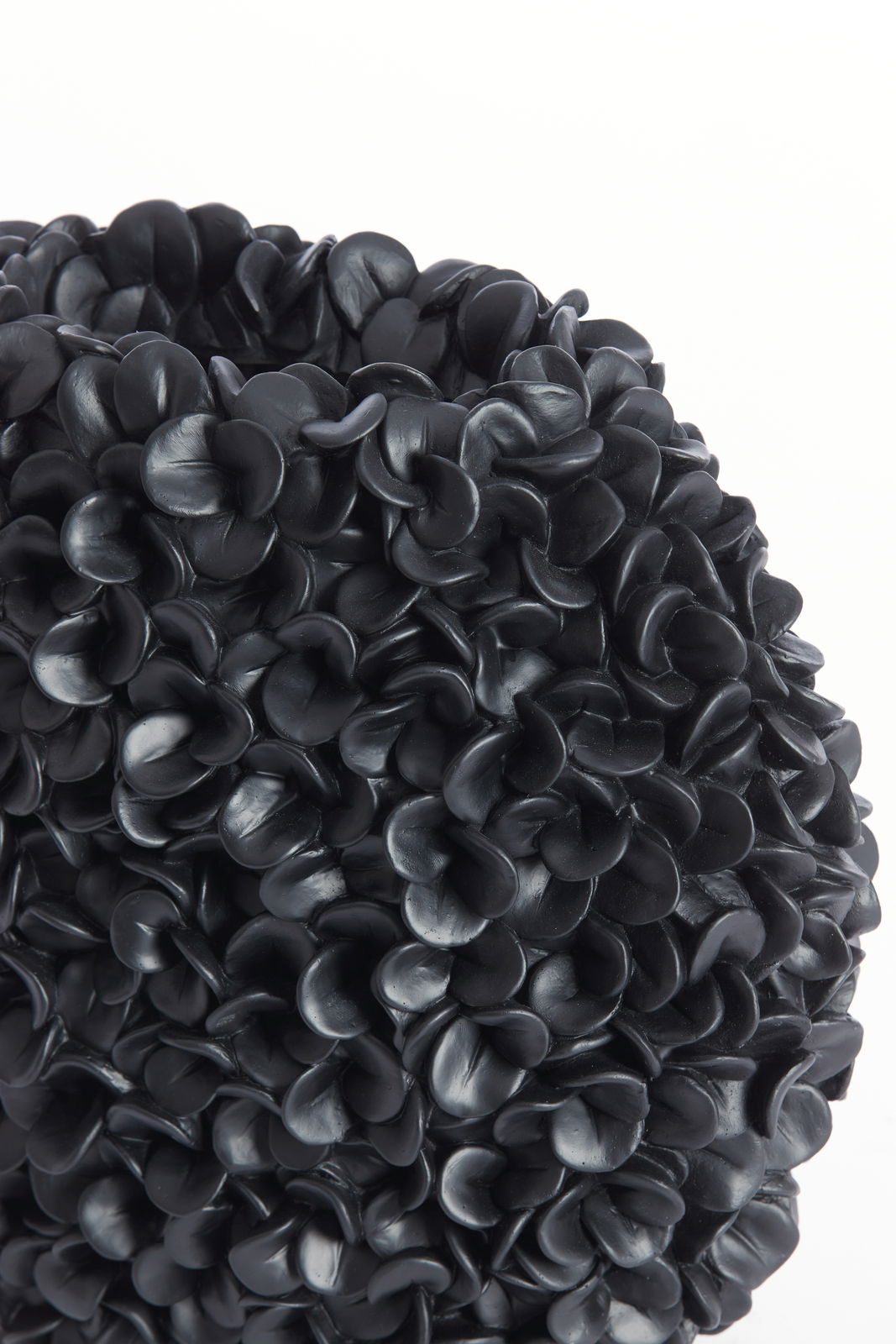 Nahaufnahme einer dekorativen Vase mit schwarzer, blütenartiger Struktur, seitliche Perspektive.