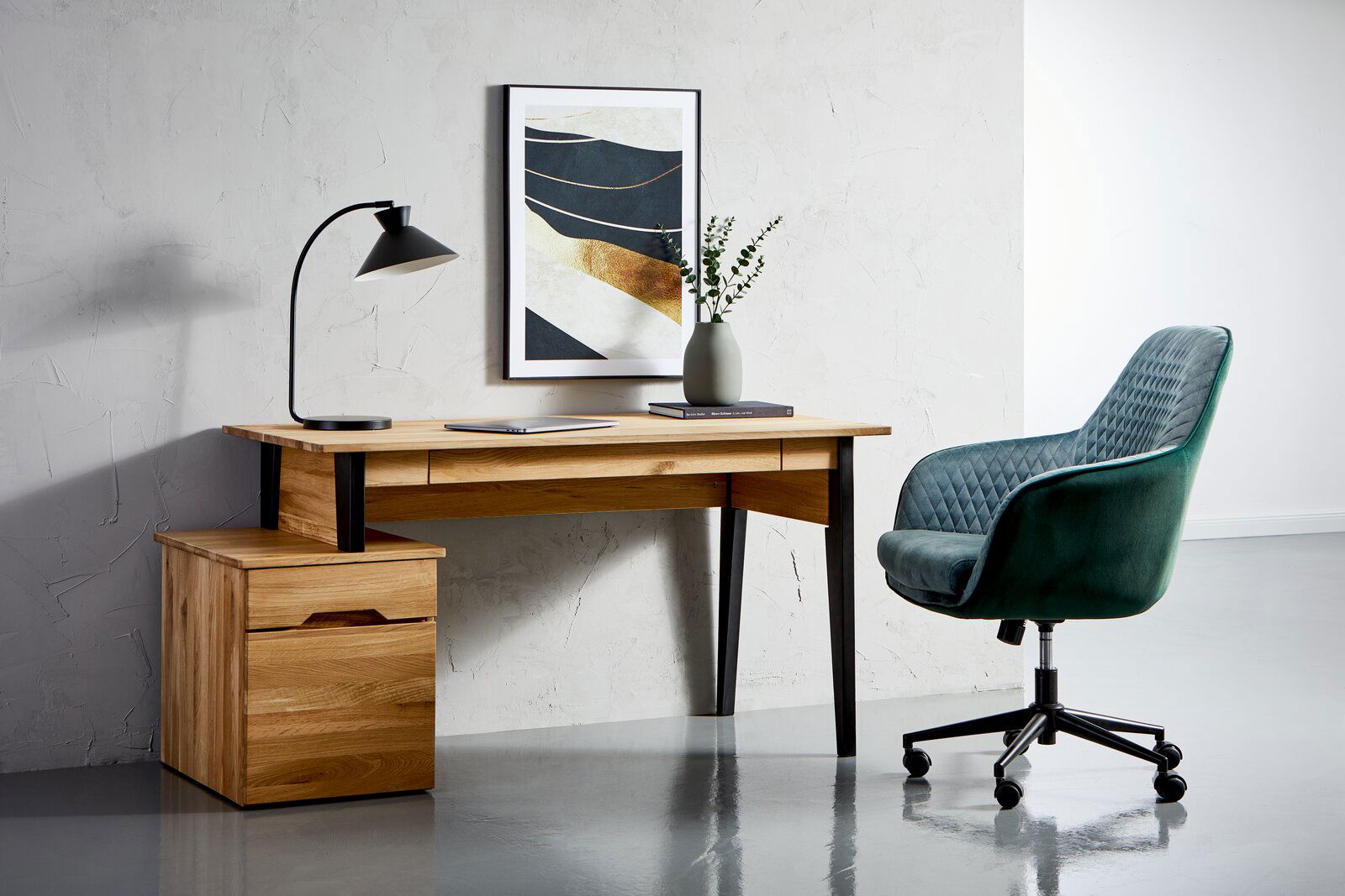 Linea Natura Schreibtisch MIRCO 1 Moderner Schreibtisch aus Holz mit schwarzem Metallgestell, seitlich mit Schubladenblock, abgebildet in einem stilvollen Büro mit grünem Drehstuhl und Wanddekoration. Perspektive von vorne.