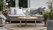 Moderne Akku-Stehleuchte SUAREZ in einem gemütlichen Wohnzimmer mit Rattanmöbeln und Pflanzen, seitliche Perspektive.